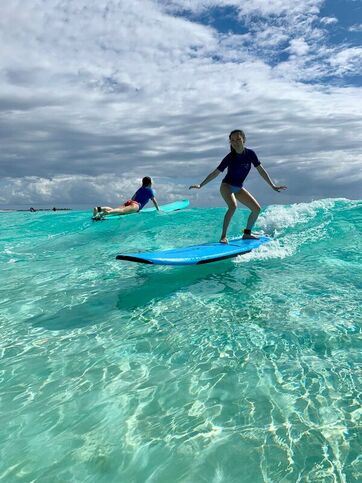 girl standing on surfboard during a surf lesson on the crystal waters in Cancun